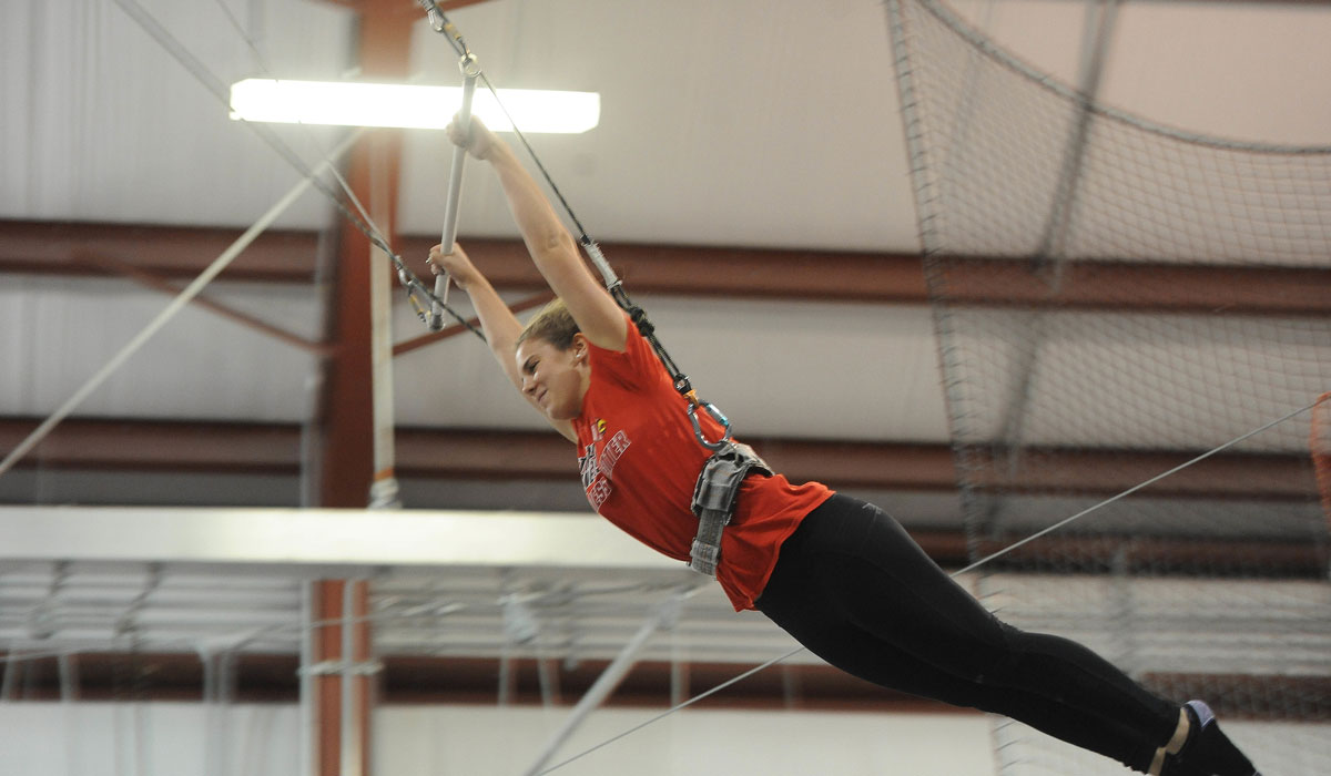 Female student flying through the air during trapeze school